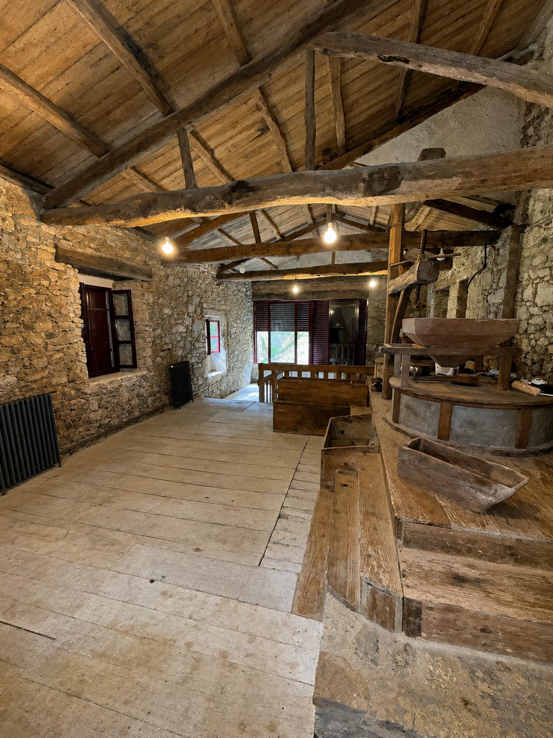 Interior del molino con estructura de madera original y maquinaria de molienda conservada